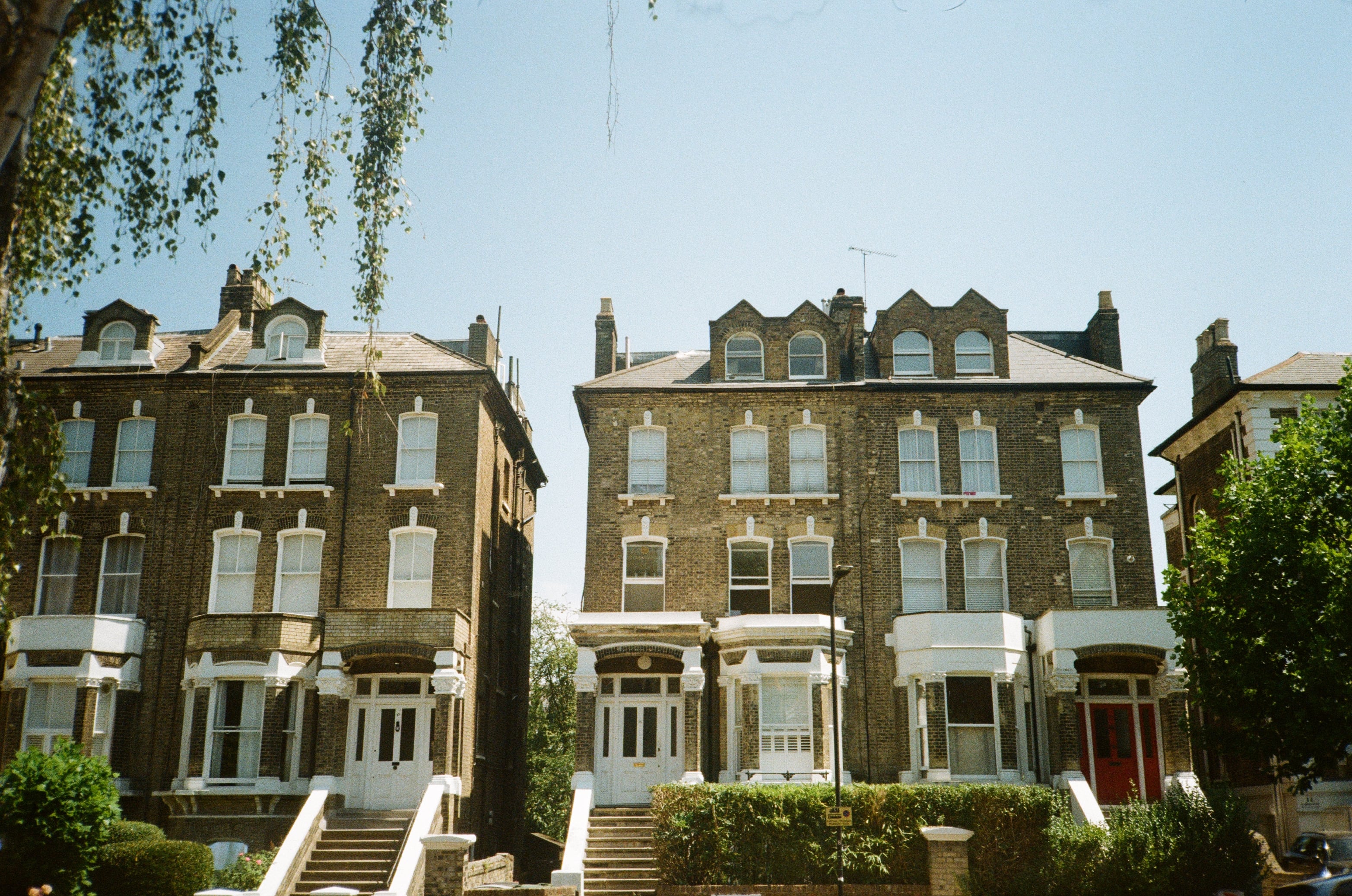 A row of tall brick houses behind trees