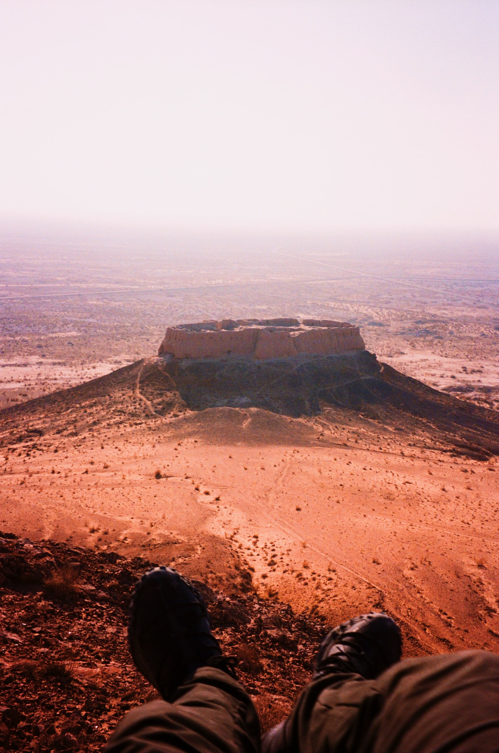 Legs outstretched above a hazy red plain and a flat-topped hill