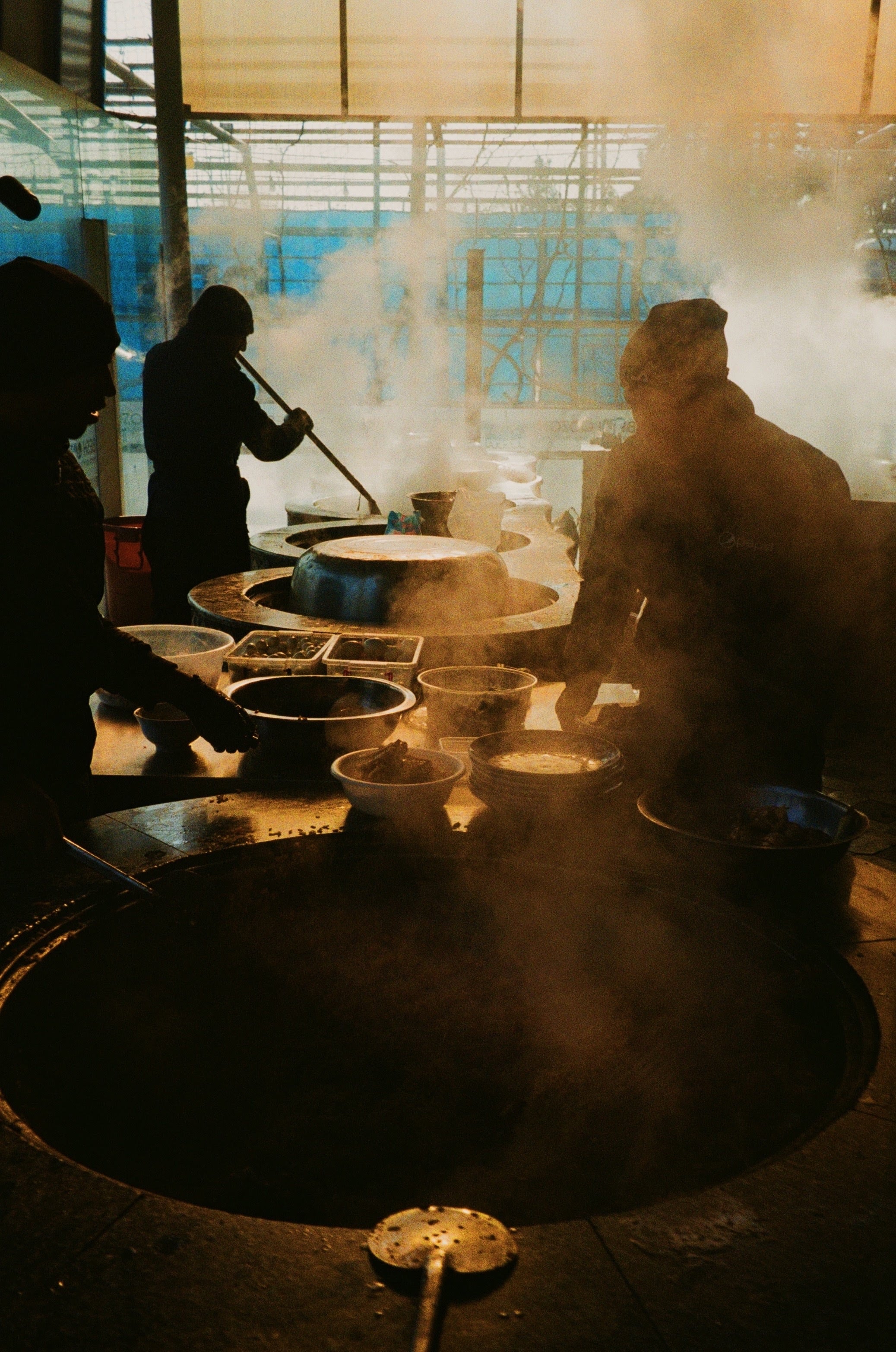 Steam rising around cooks at a large pot