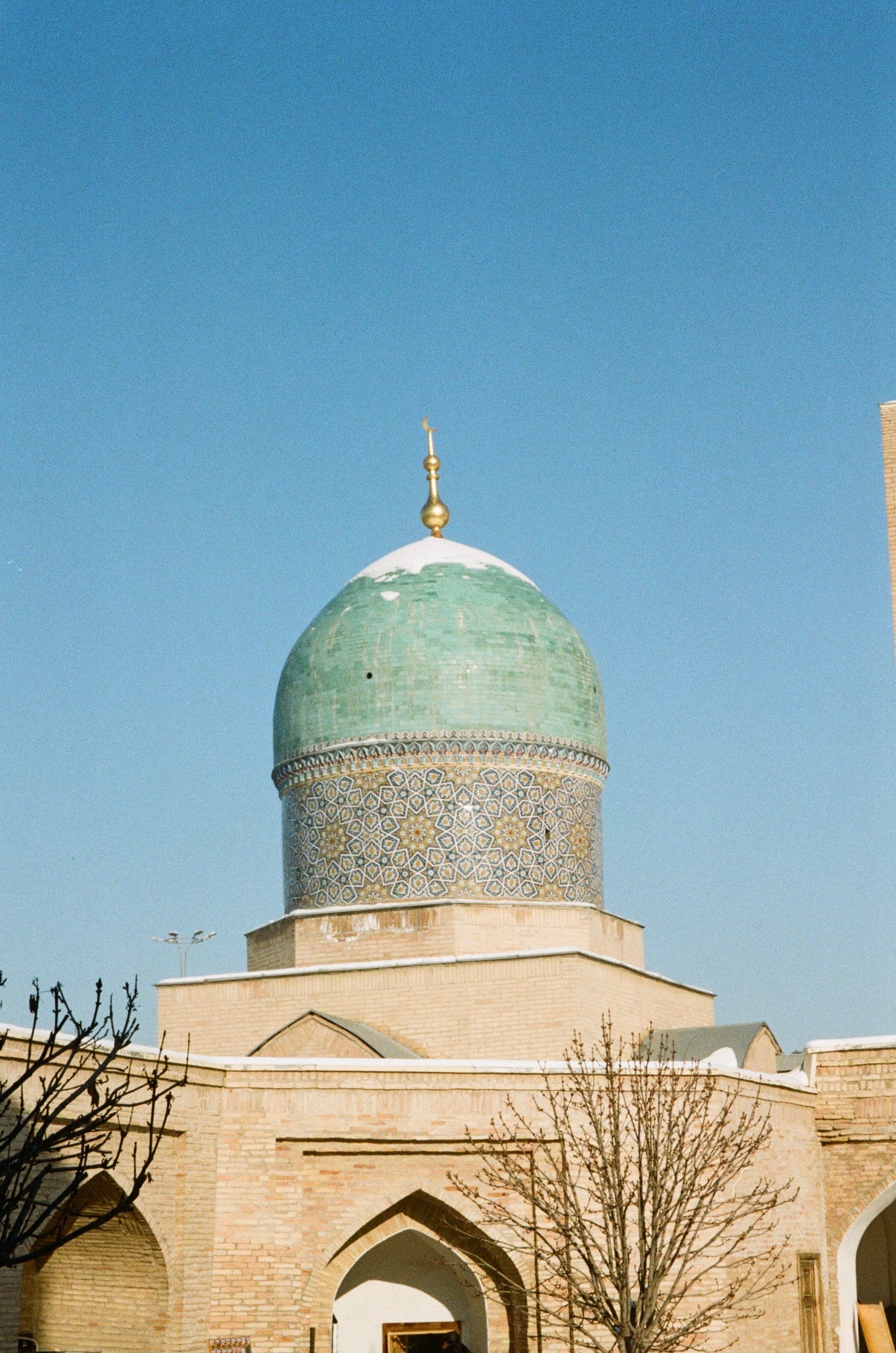 A green-tiled dome above an arcaded building