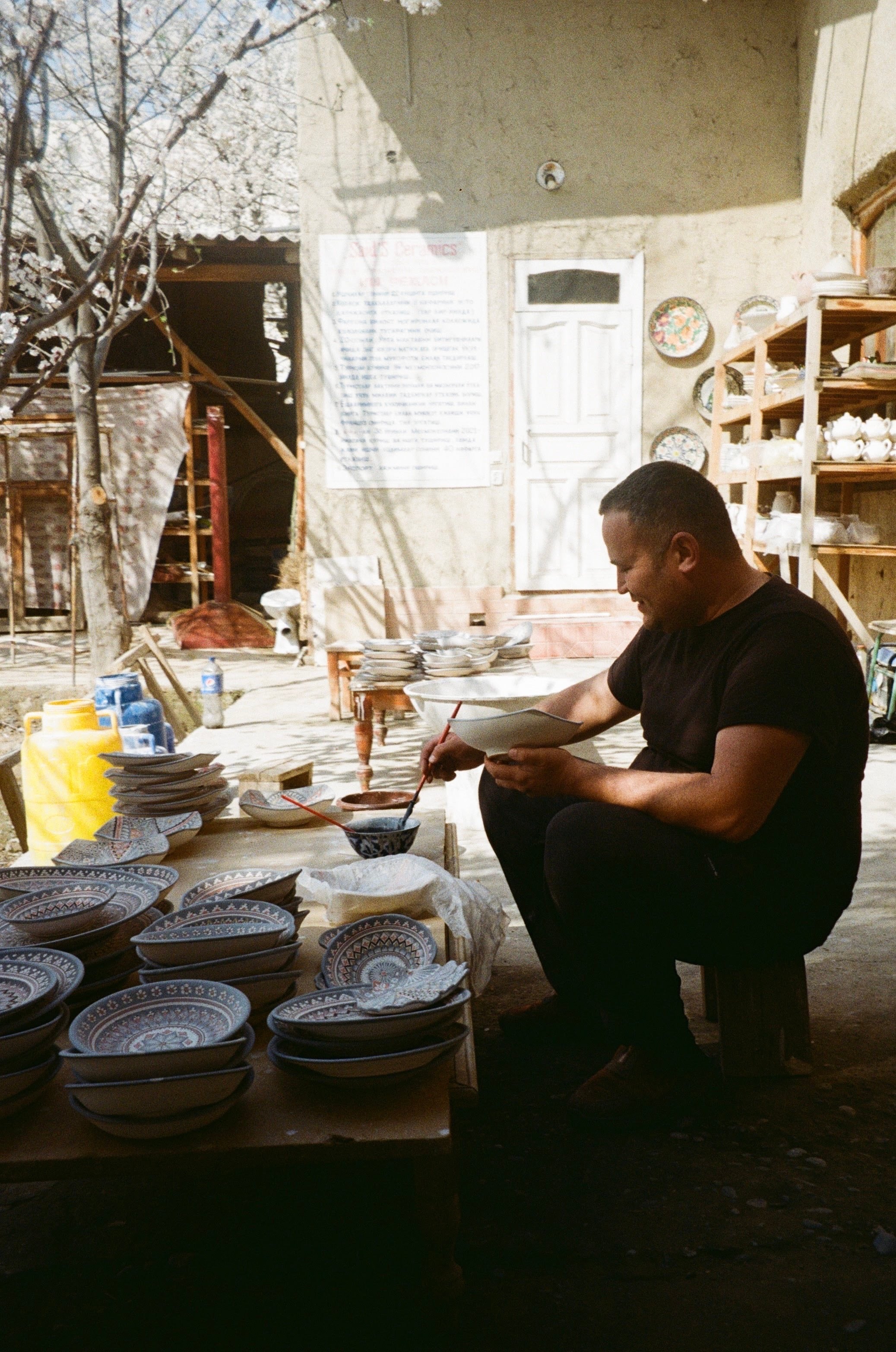 A craftsman seated at work in a cluttered workshop