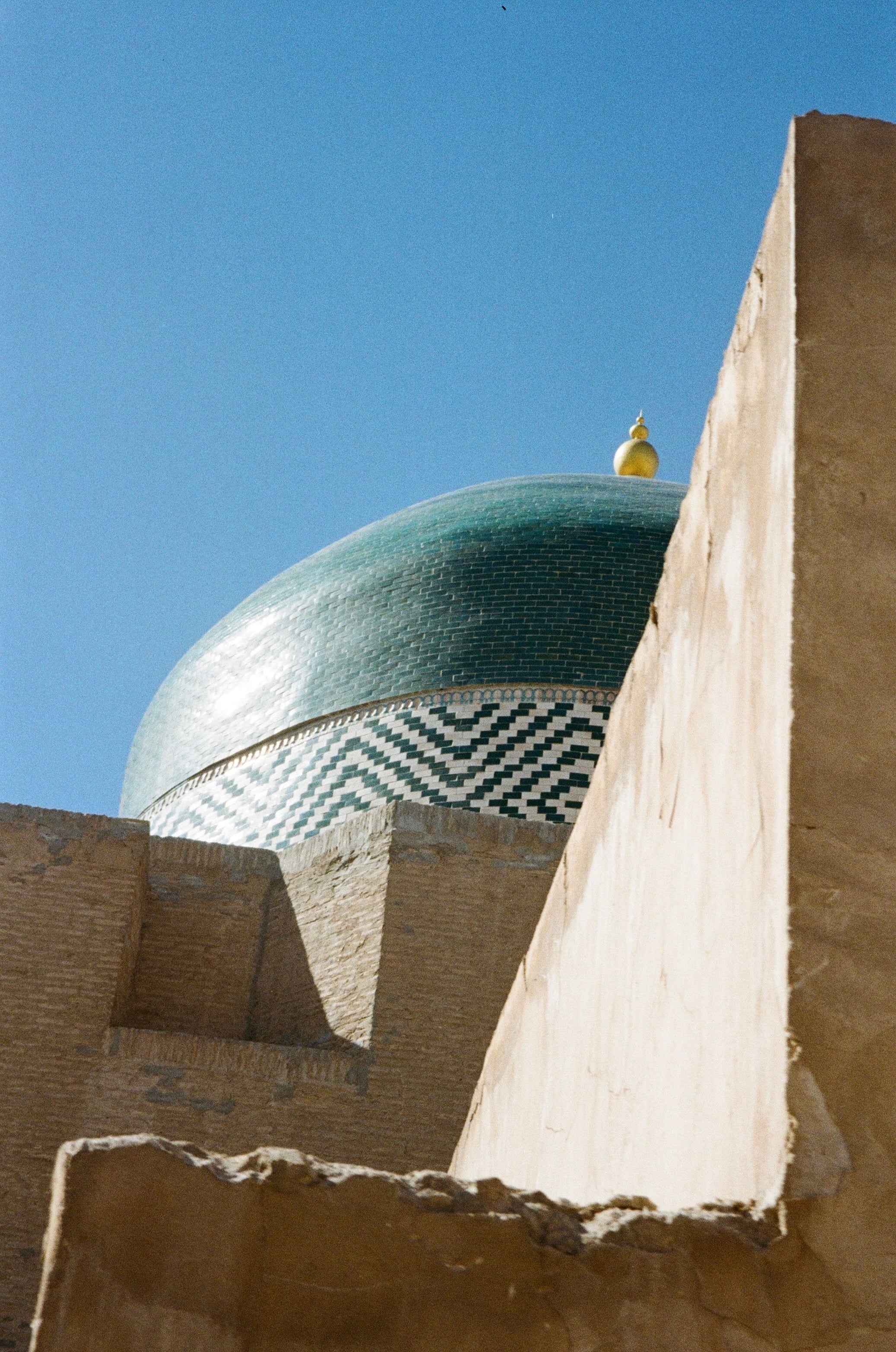 A turquoise dome rising behind a pale wall