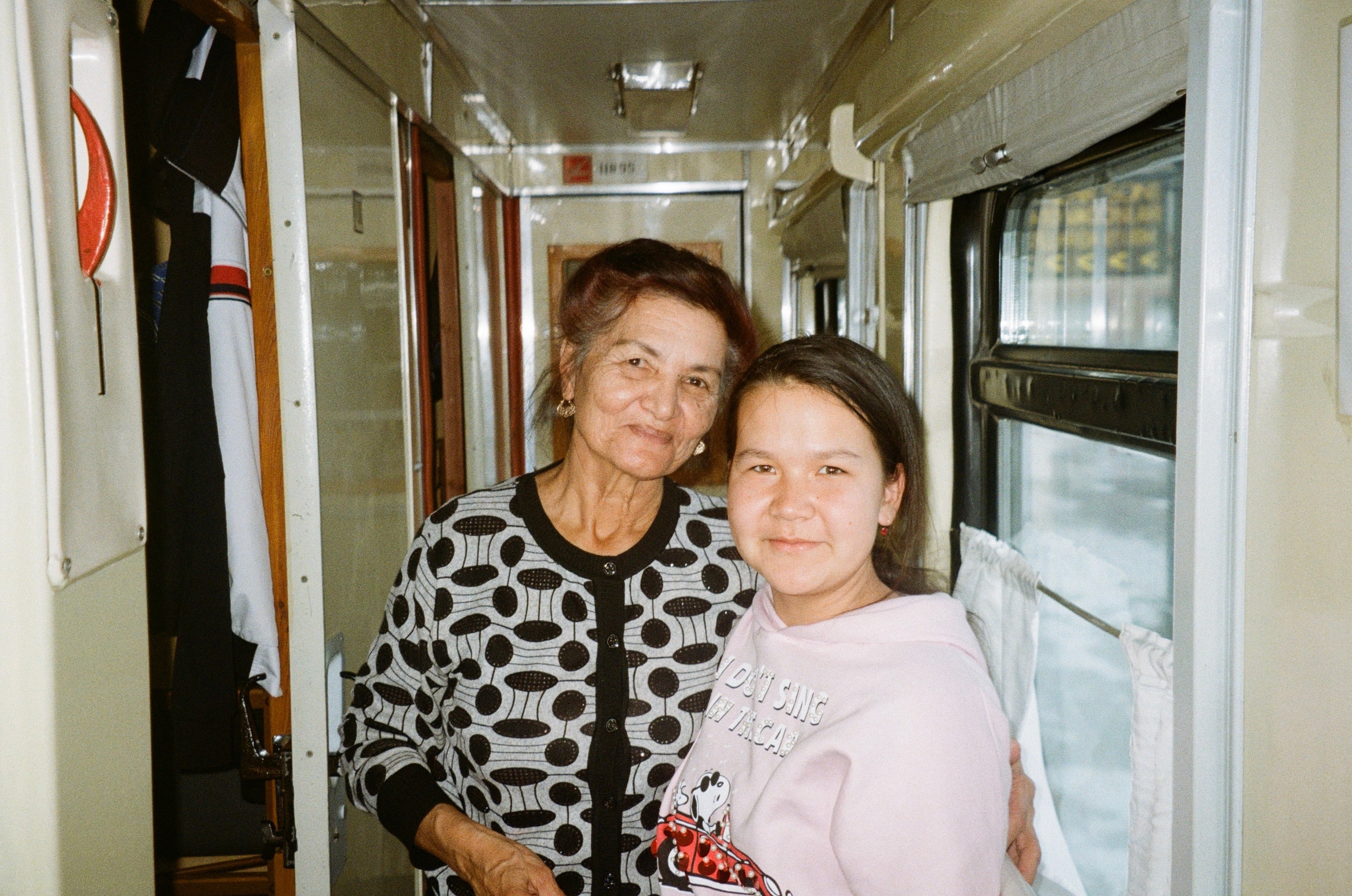 Two women smiling in a train corridor