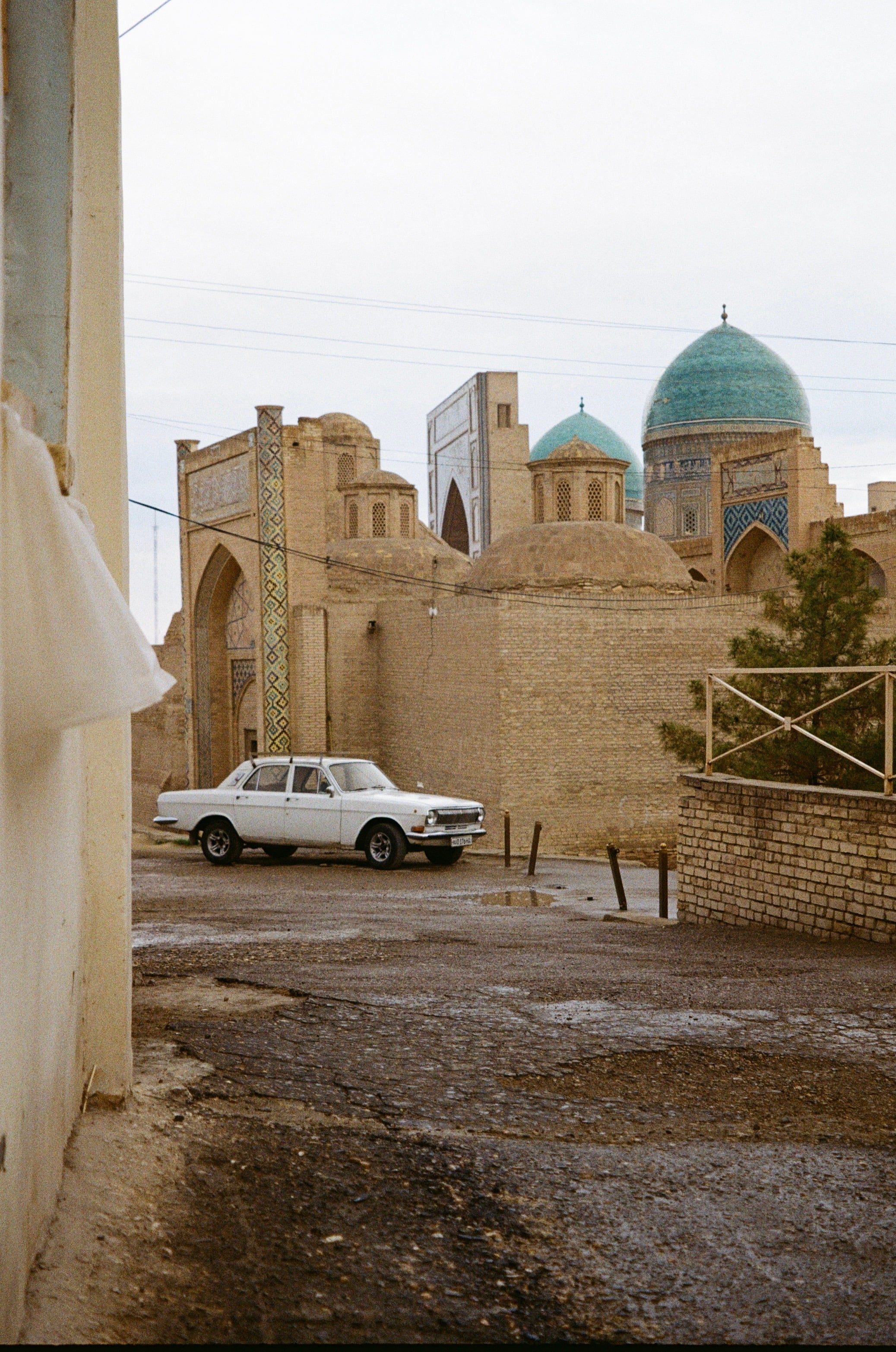 A dusty lane of domed buildings with a parked white car
