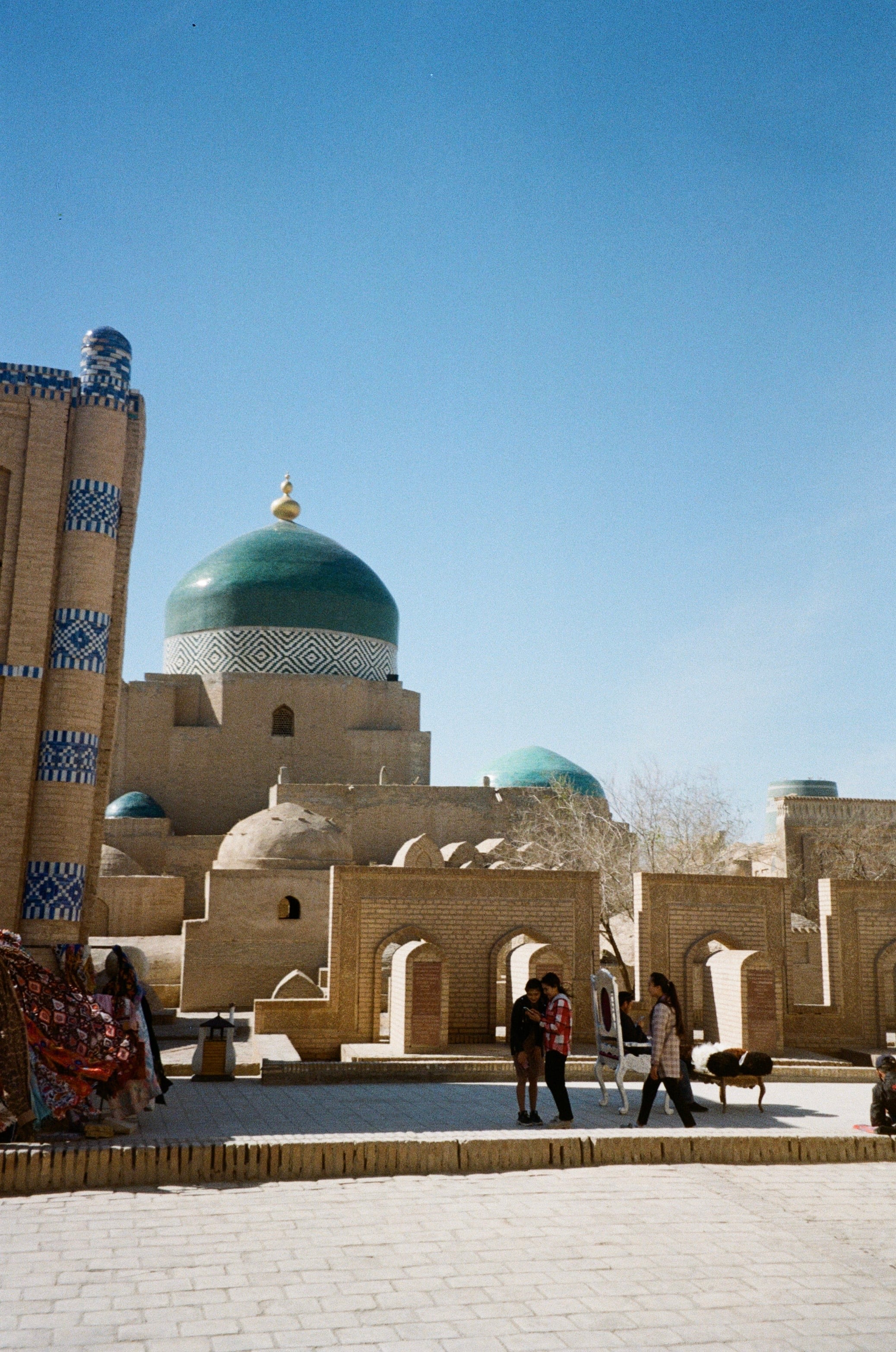 A square with a blue-domed building and people crossing