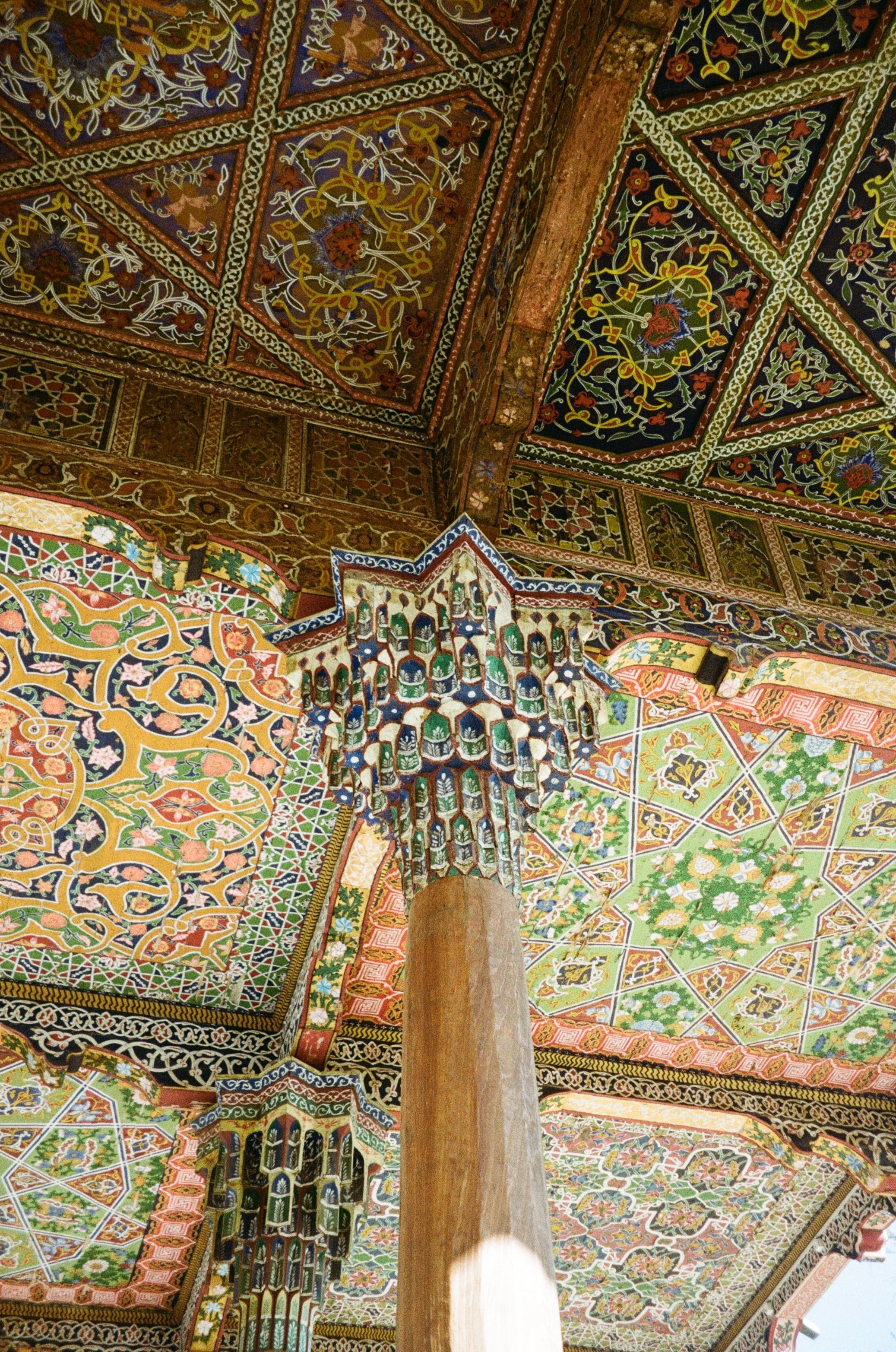 A painted, carved wooden ceiling above a column