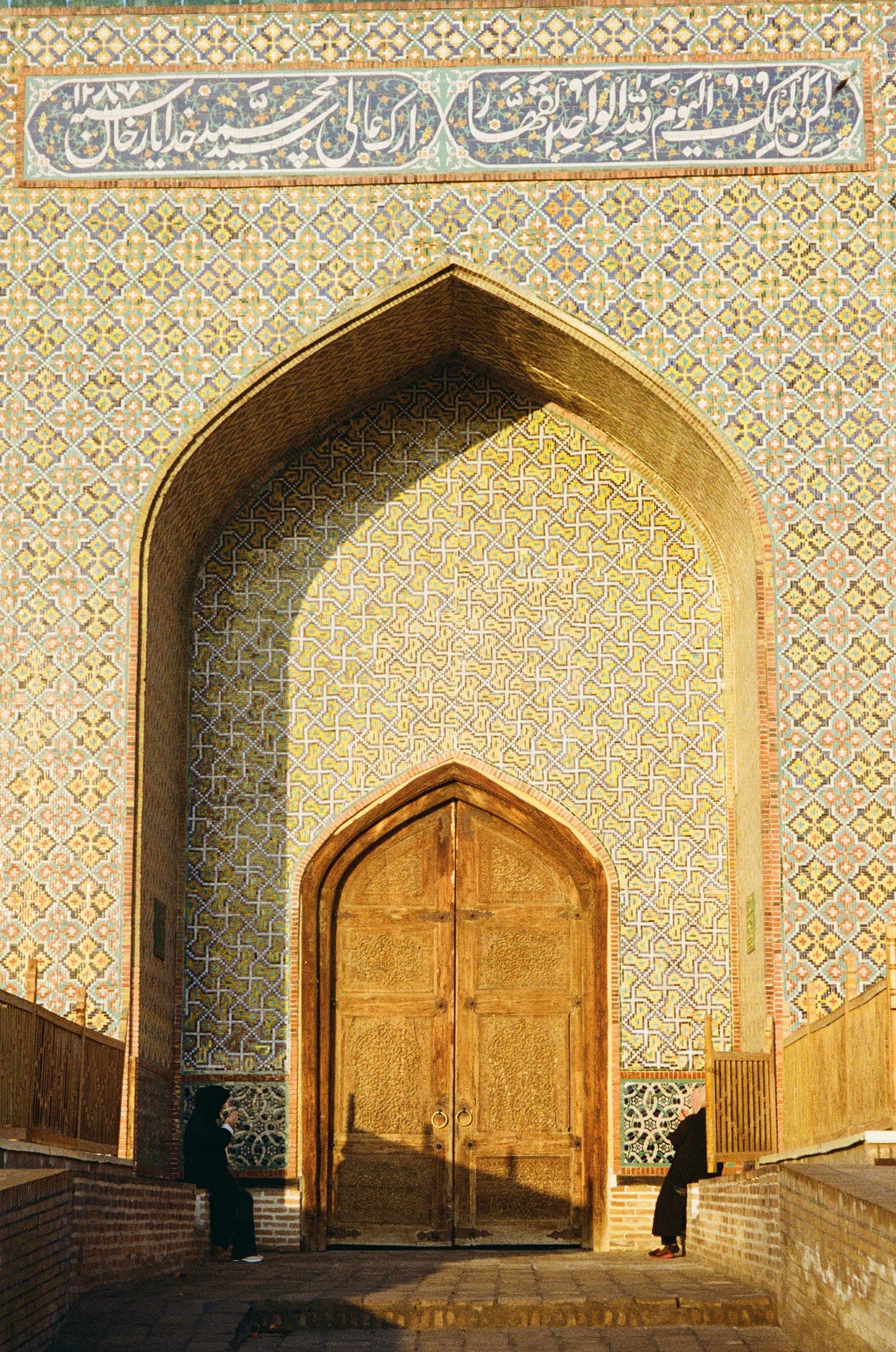 A tiled arch framing a carved wooden door