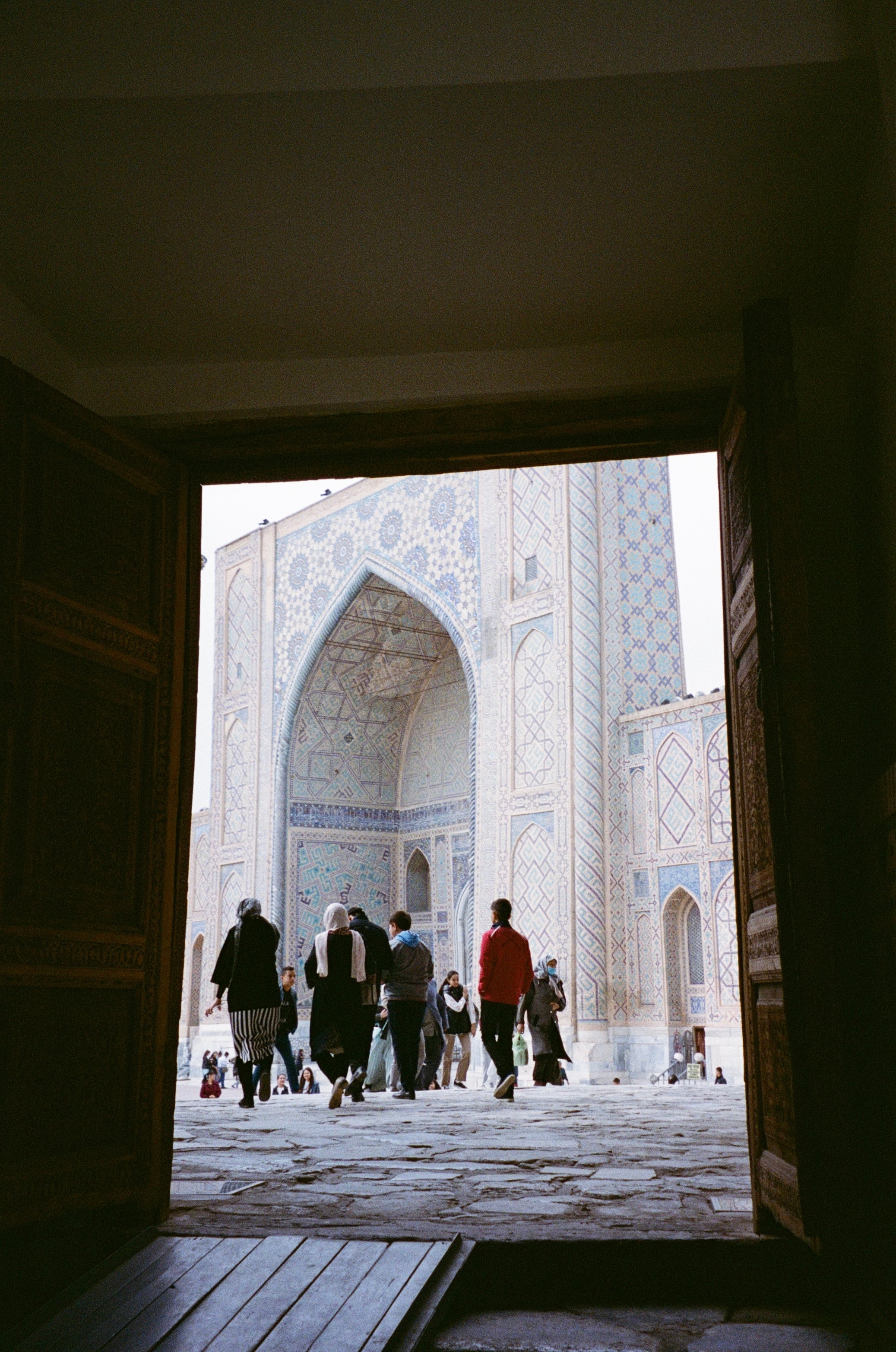 Looking out of a dark doorway towards a sunlit courtyard and people