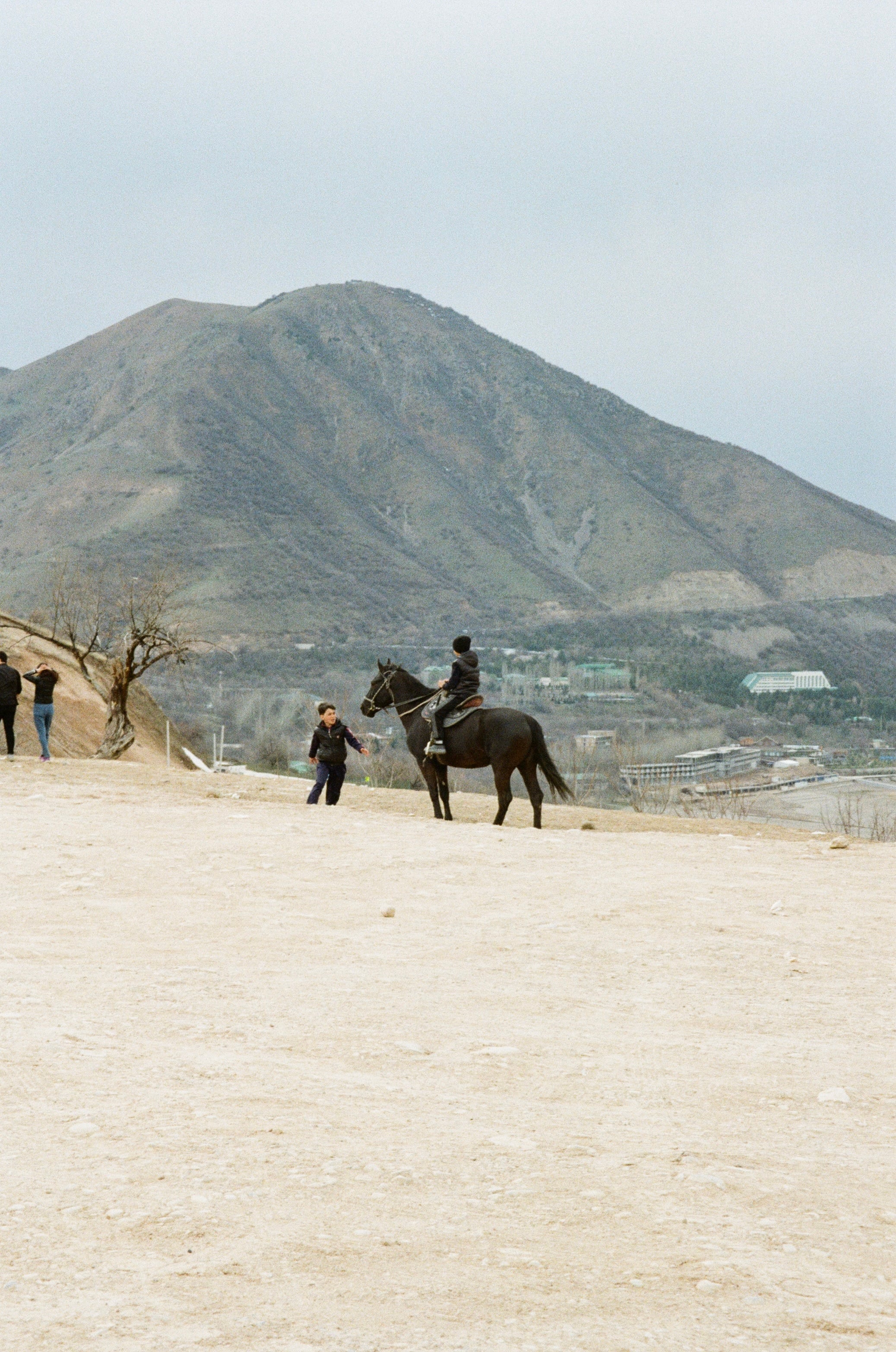 A rider on horseback before a bare mountain
